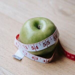 Green apple with measuring tape on table in kitchen